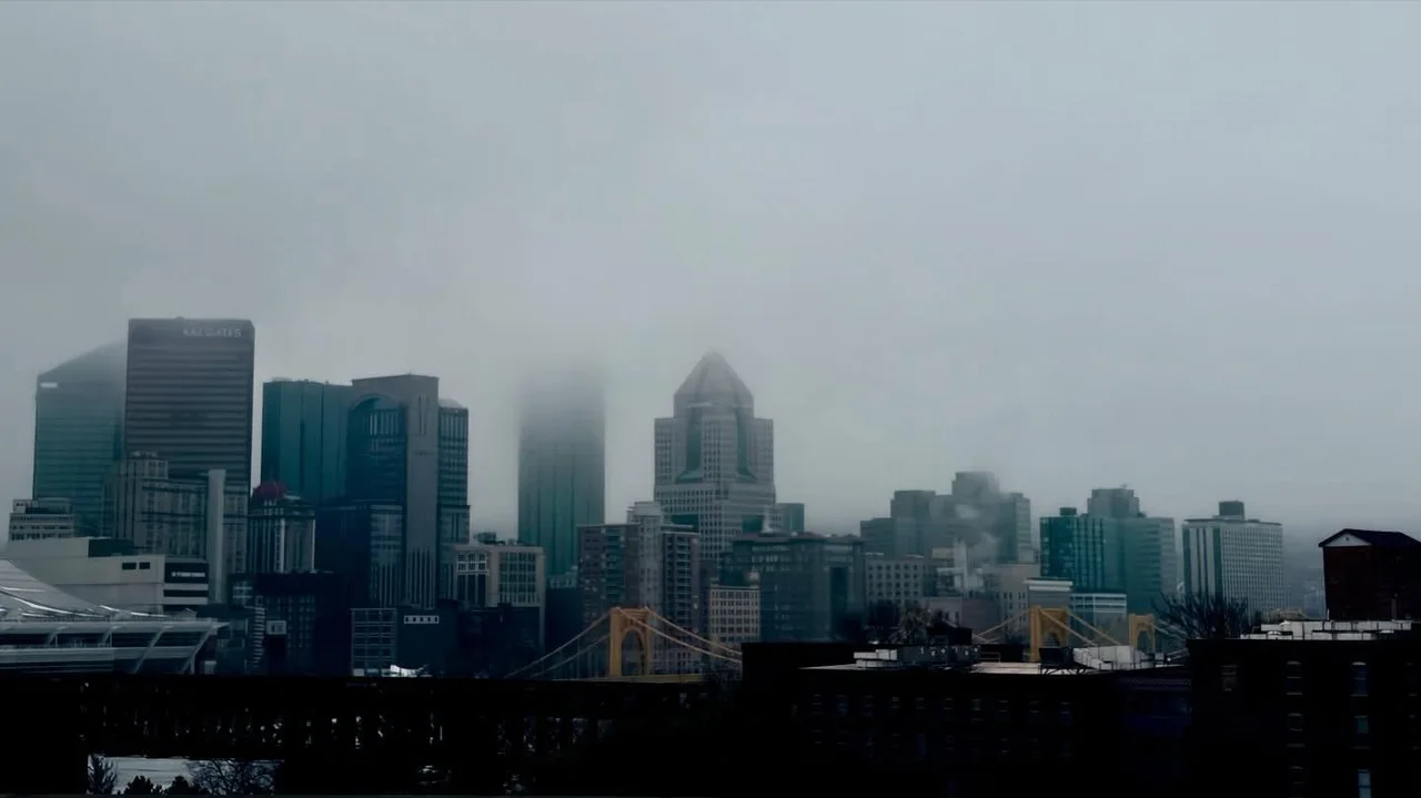 A city skyline fading into dense gray fog.